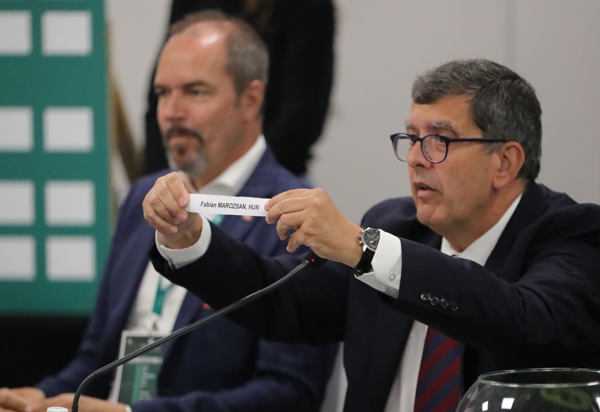 Javier Moreno referee felmutatja a magyar éljátékos nevét viselő cédulát. A háttérben Jürgen Roth, az osztrák tenisz szövetség alelnöke